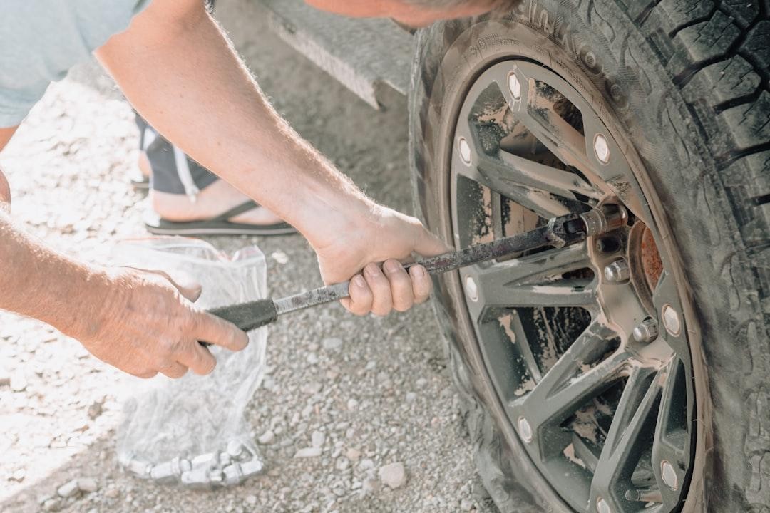 Person inflating a car tire with a portable pump