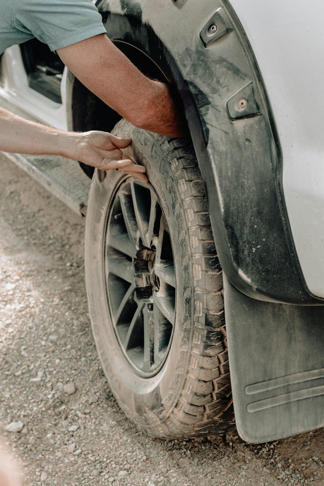 Person inspecting a car tire in the wheel well