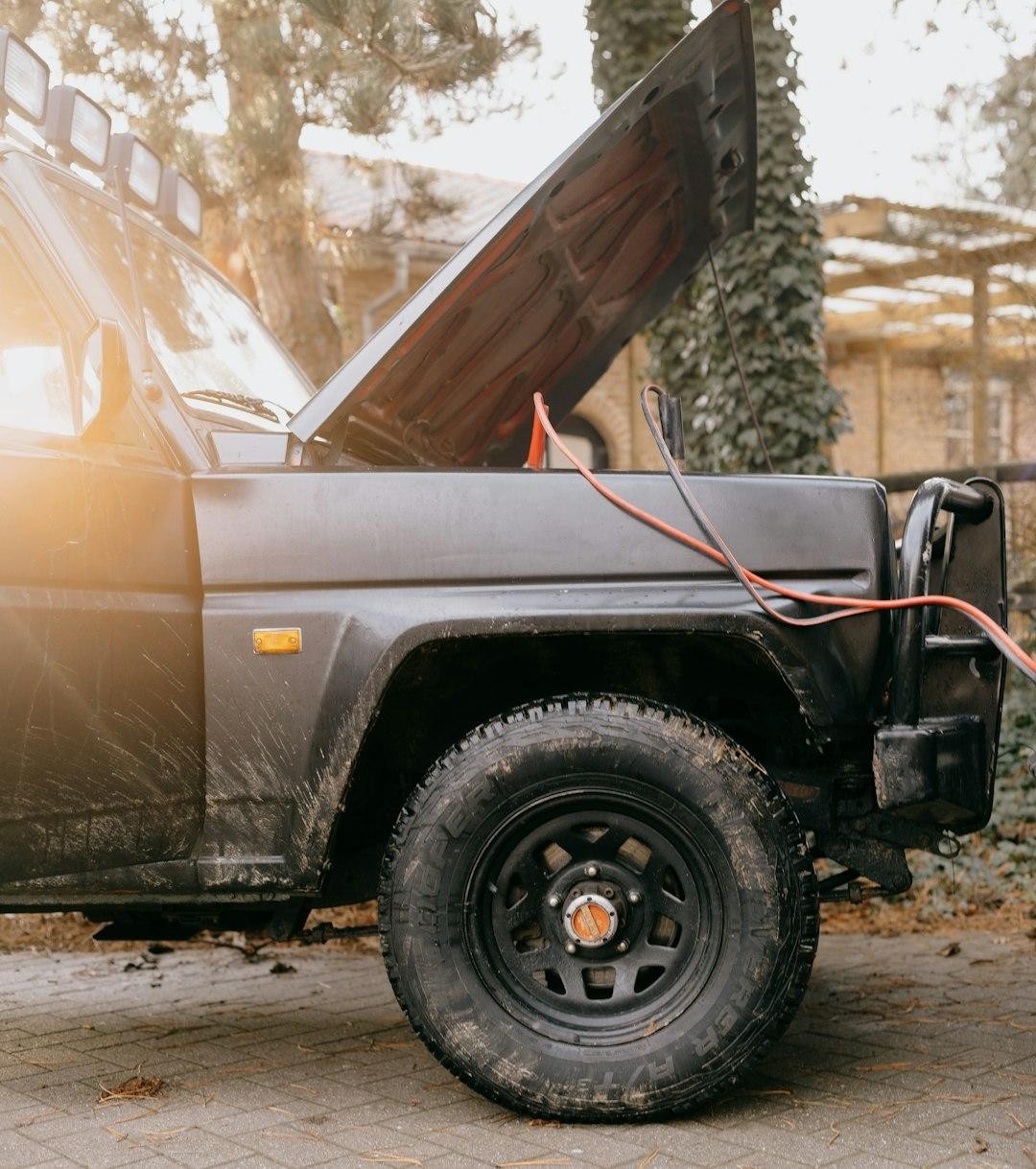 A car with its hood open and jumper cables attached to the battery