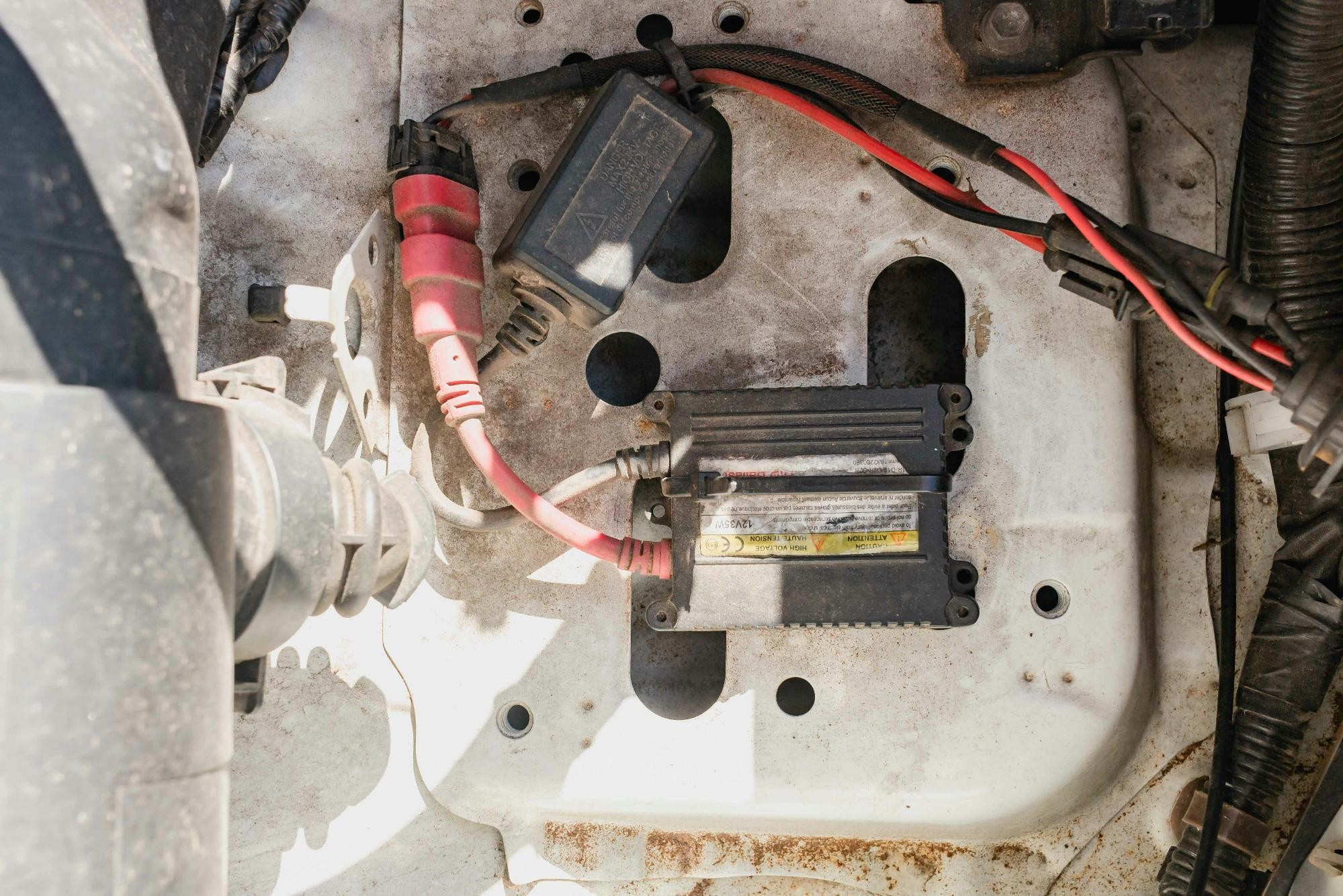 Close-up of car engine components including wiring and a small electronic module