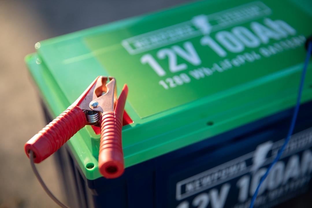 A 12V 100Ah battery with red and black jumper cables attached to the terminals