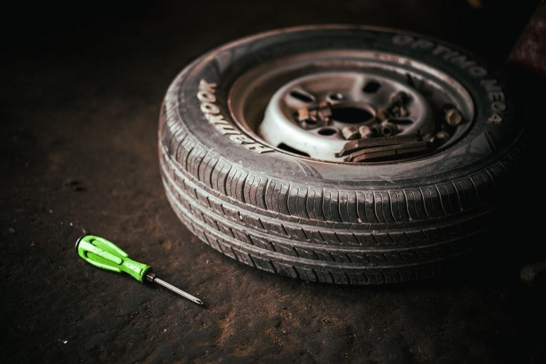A tire next to a screwdriver on a dark surface