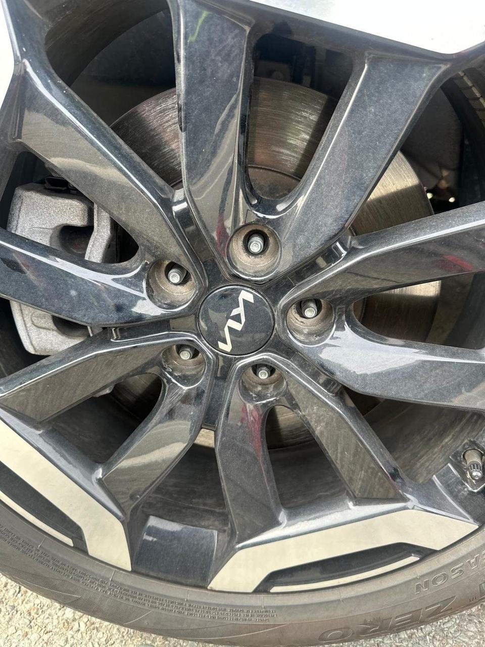 Brake rotor and caliper seen through the spokes of a black alloy wheel