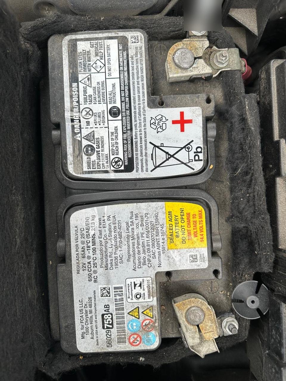 Label on a sealed AGM battery in its tray, showing 12V, 65Ah and 650 CCA, with the terminal clamps at each end