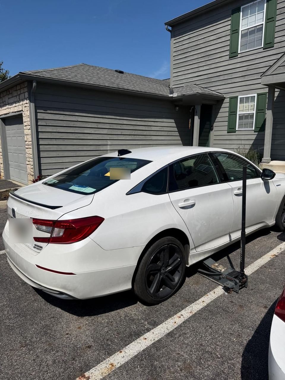 White Honda Accord raised on a floor jack in an apartment parking lot during a tire service call