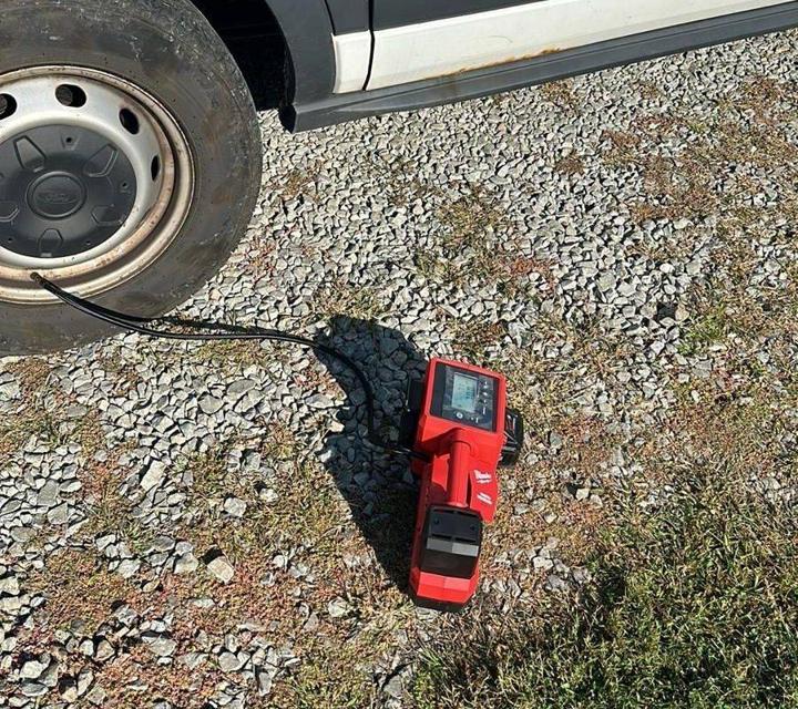 Red portable tire inflator on gravel with its hose connected to the valve of a van's steel wheel