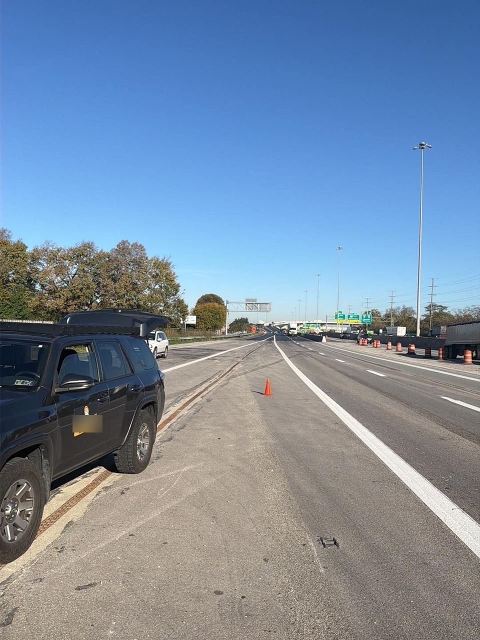 Grey Roadmate service truck parked on a highway shoulder with an orange cone set out on the pavement