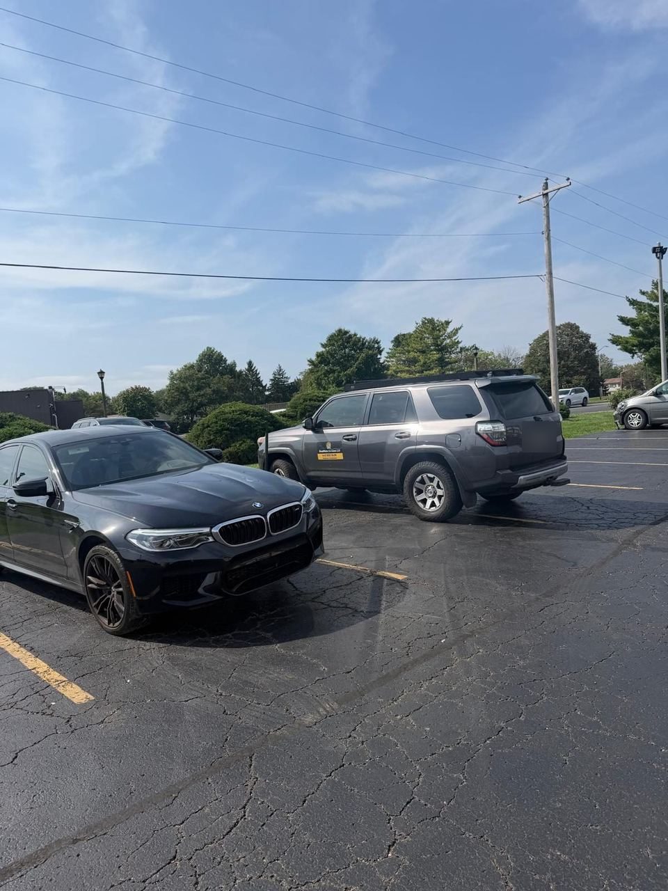 Grey Roadmate service truck parked behind a black BMW sedan in a parking lot