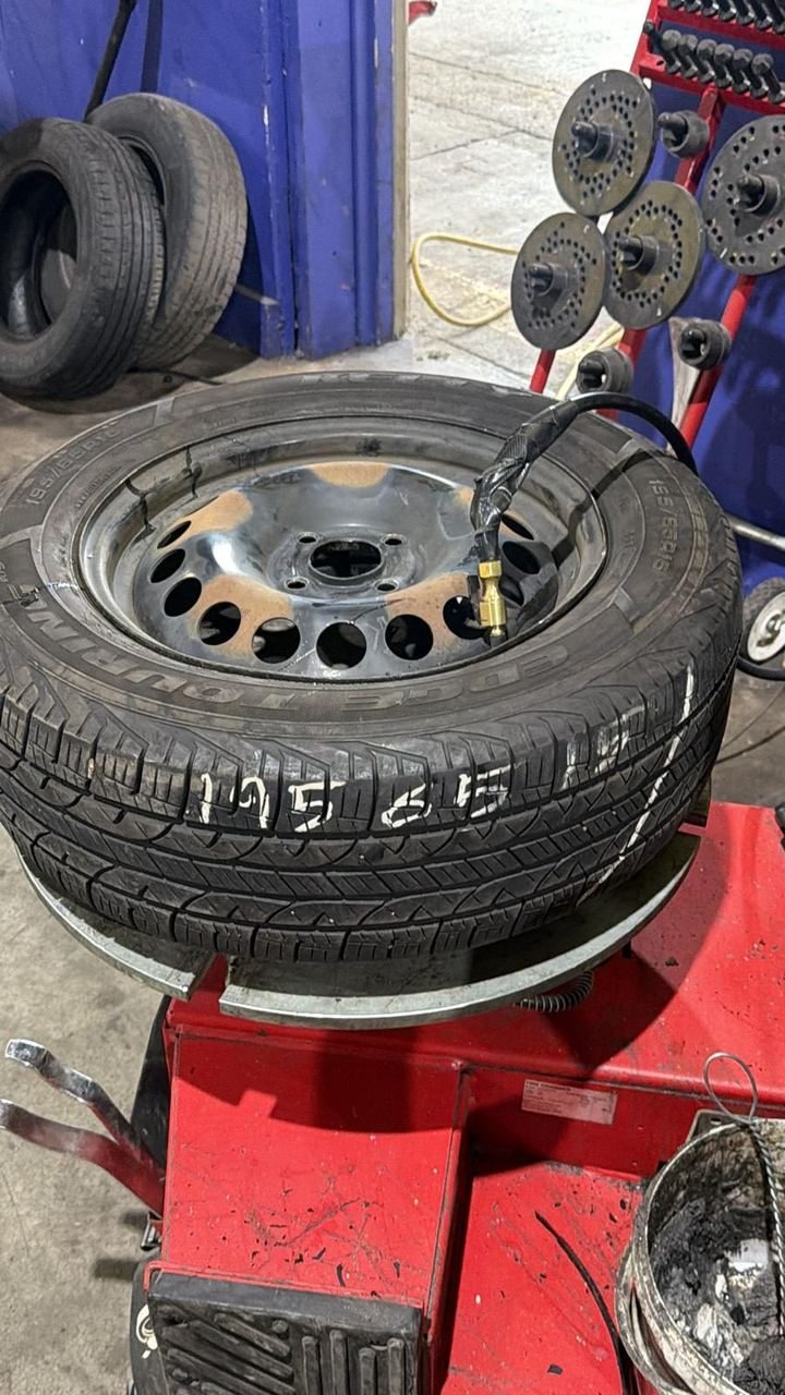 Tire mounted on a steel wheel sitting on a red tire changer machine in a tire shop