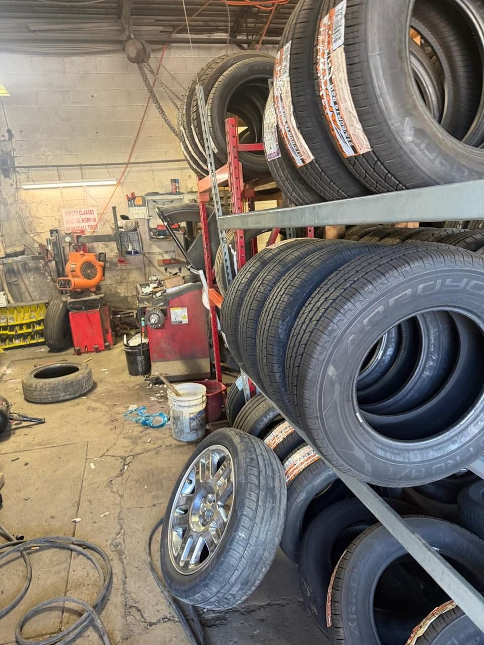 Tire shop with racks of new tires, a tire changer machine and a wheel balancer against the back wall