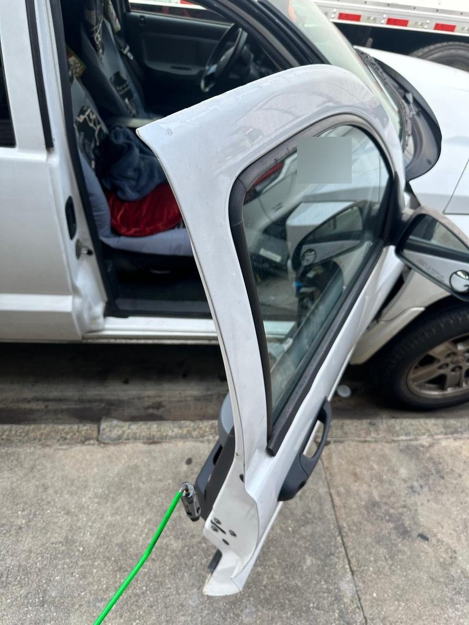 White SUV at a curb with the driver door open and a green line running to the door latch